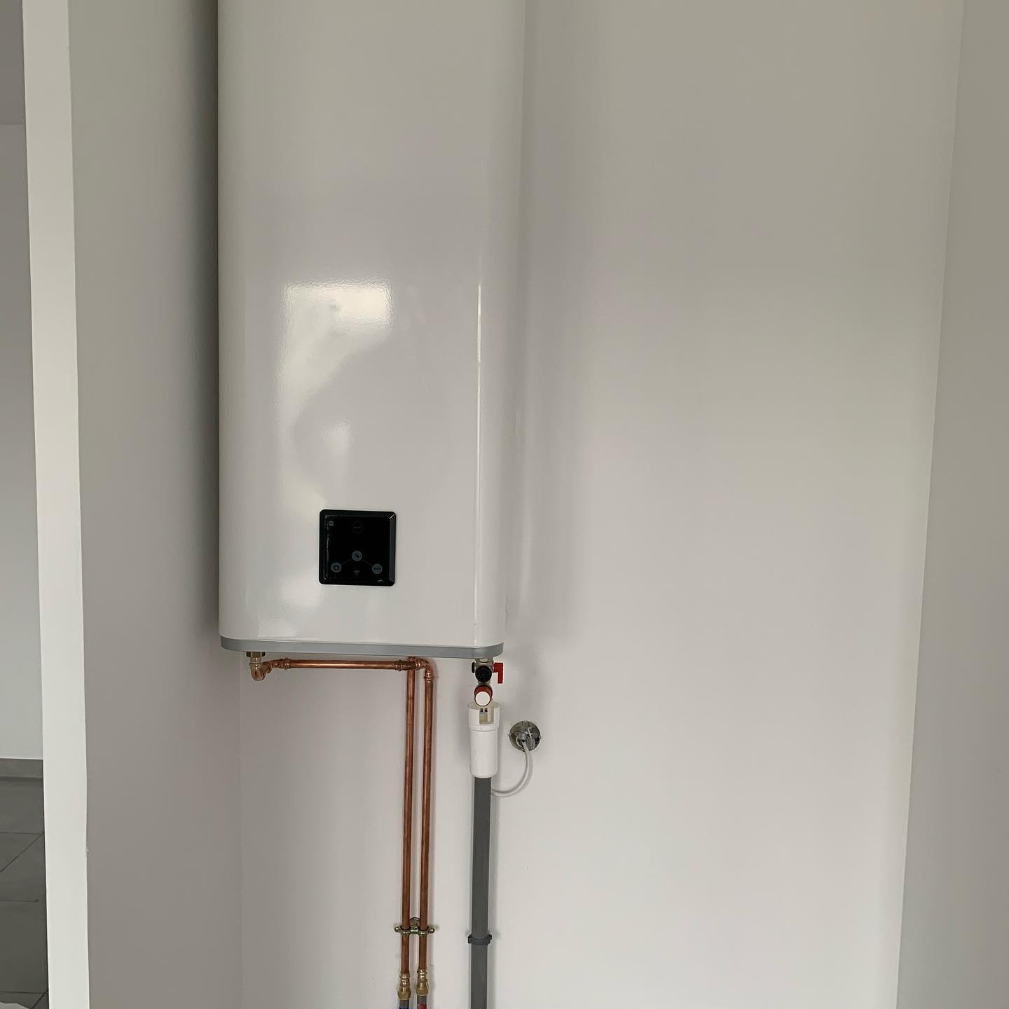 Ballon d'eau chaude installé proprement avec robinetterie maintenue.