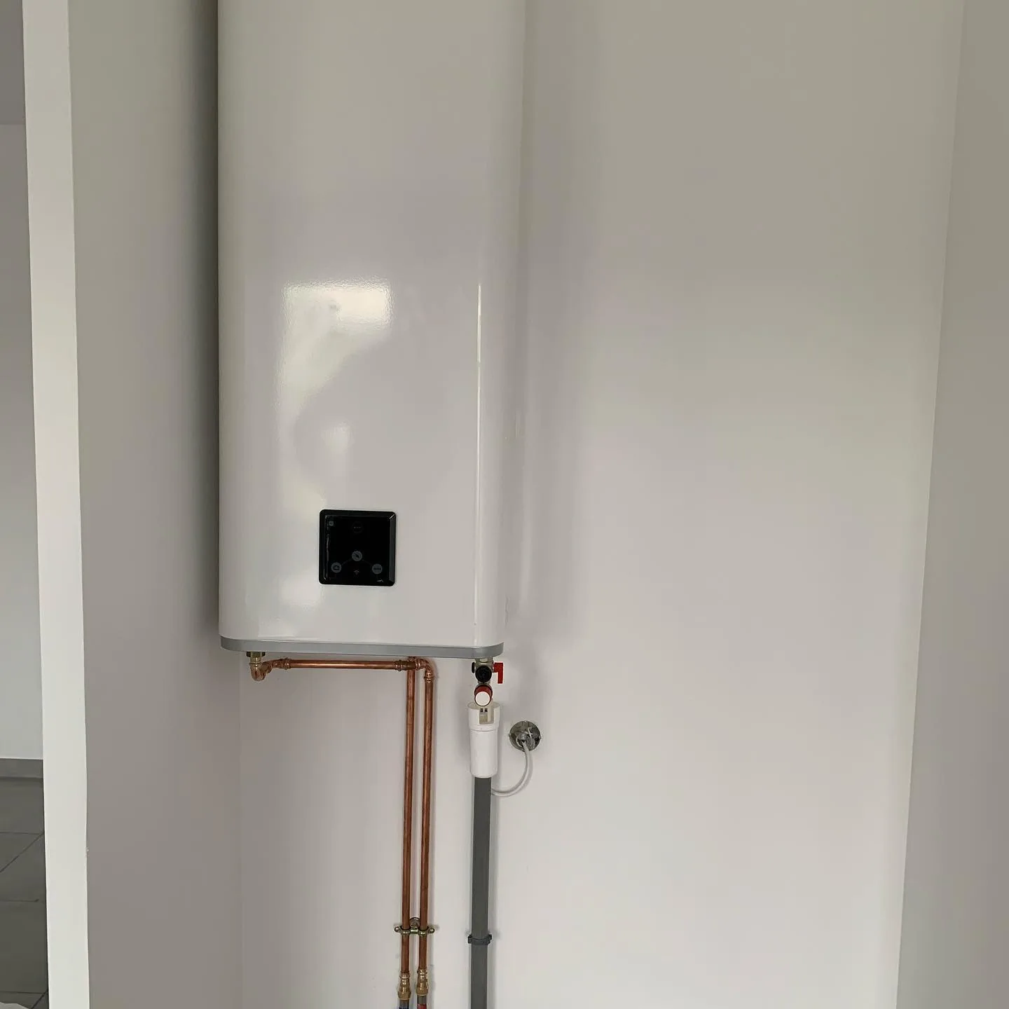 Ballon d'eau chaude installé proprement avec robinetterie maintenue.