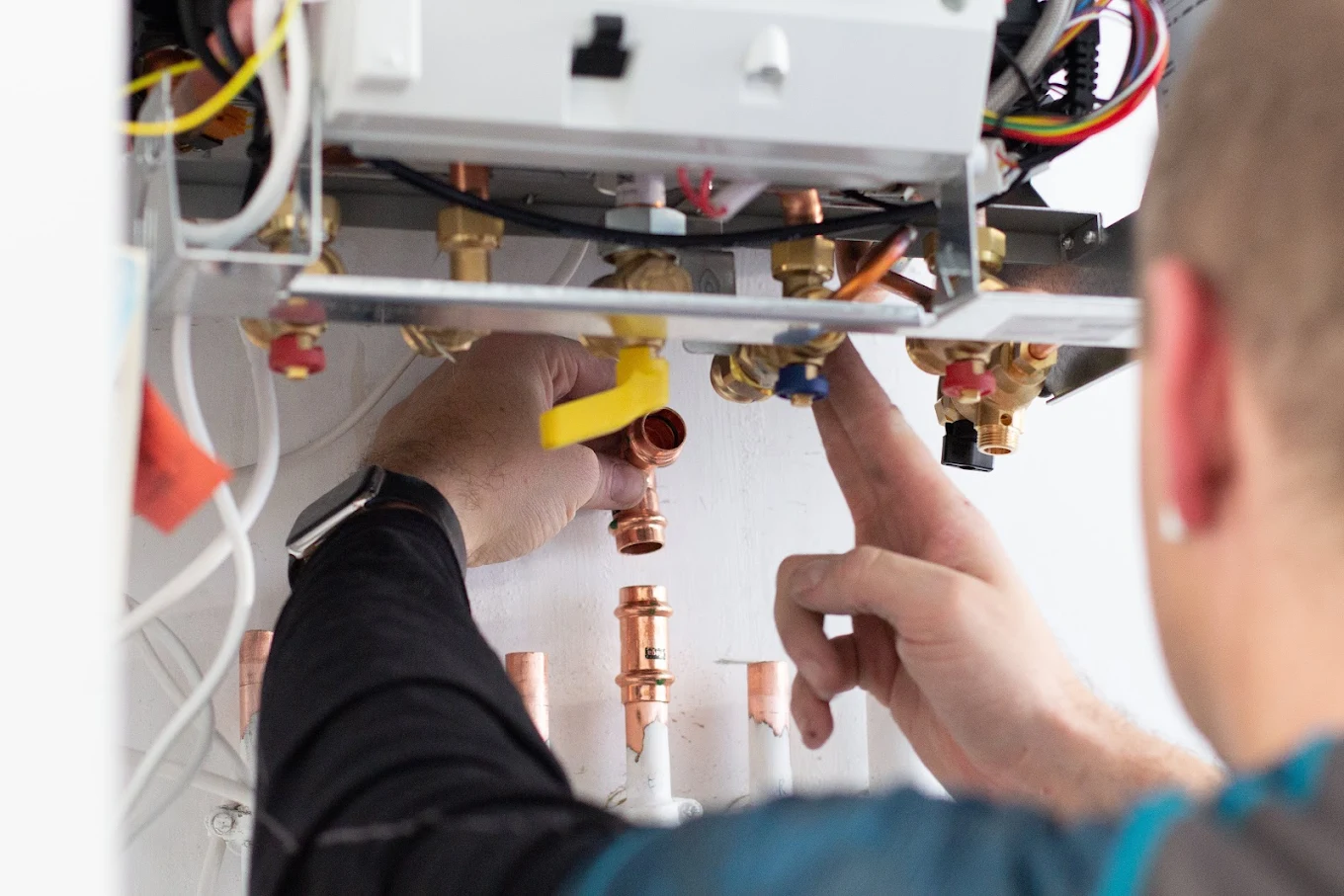 Mains de technicien Rakor sur raccords laiton et tuyauterie cuivre.