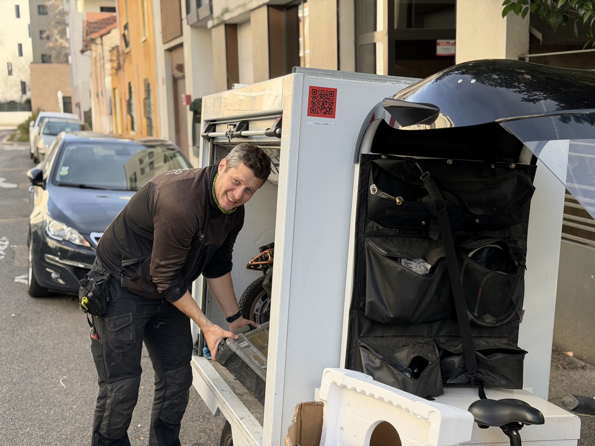 Rémy chargeant le coffre du vélo cargo dans une rue de Lyon.